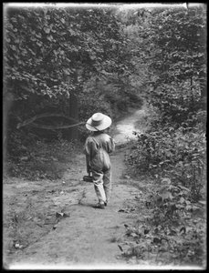 William Gray Hassler mit Strohhut und Latzhose, trägt Angelrute und Korb, geht allein einen Pfad im Wald entlang, 20. August 1911