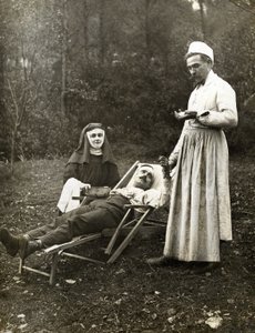 Arzt misst den Puls eines verletzten Mannes, assistiert von einer Krankenschwester-Nonne, ca. 1900