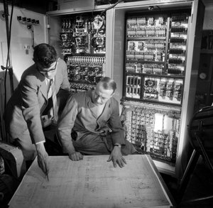 Ingenieure diskutieren Pläne vor dem elektronischen Bedienfeld, das sie gebaut haben