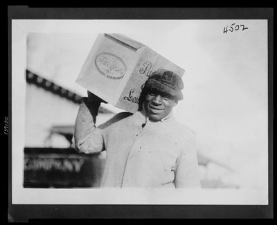 Afroamerikanischer Mann trägt eine Kiste "Four Roses" Whiskey auf der Schulter, möglicherweise vom US-Internal Revenue Bureau beschlagnahmt von American Photographer
