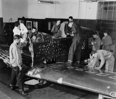 Soldatenschüler arbeiten an einem "Flying Patch," einem Curtiss "Warhawk"-Jagdflugzeug ohne Motor oder Heckbaugruppe, mit simulierten Einschusslöchern und Flicken, ca. 1942 von American Photographer