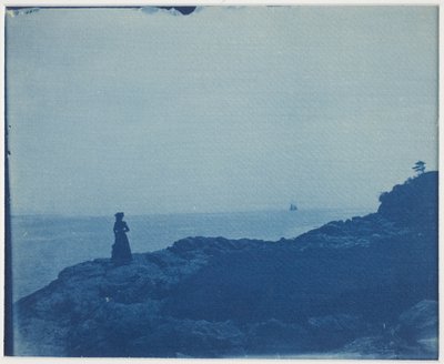 Frau beobachtet Schoner von einem felsigen Vorgebirge von American Photographer