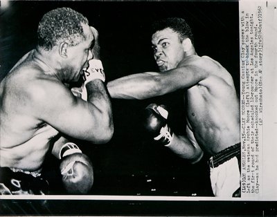 Der junge Cassius Clay trifft mit einem linken Haken gegen den Veteranen Archie Moore in der ersten Runde des Kampfes in Los Angeles von American Photographer