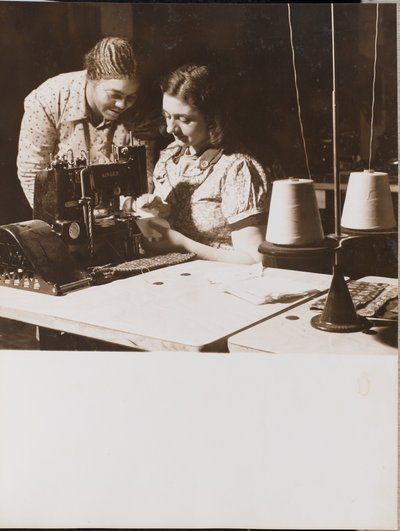 Zwei Frauen benutzen eine Nähmaschine von Arnold Eagle