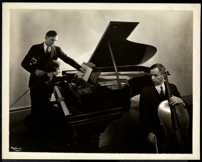 Blinde Frau, Miss Harding, am Klavier unterrichtet zwei blinde Männer an der Violine und am Cello, 1936 von Byron Company