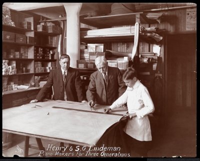 Porträt von Henry und S.G. Lindeman mit ihrem Sohn oder Enkel, der über Zeichnungen für ein Klavier steht, 1910 von Byron Company