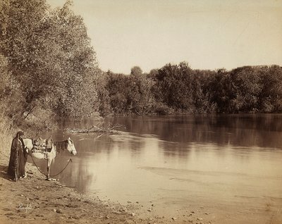 Ein Mann in traditioneller Kleidung mit seinem Pferd vor einem See in Ägypten von Félix Bonfils