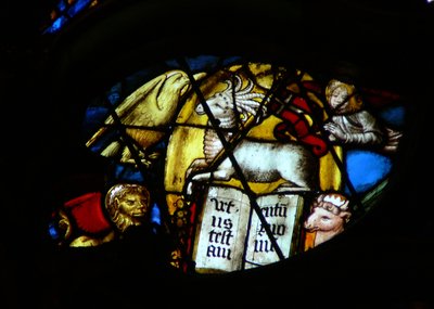 Das Westrosenfenster zeigt eine Szene aus dem Buch der Offenbarung: Lamm mit sieben Hörnern und sieben Augen öffnet das Buch. Beachten Sie die Symbole der vier Evangelisten (5:7). von French School