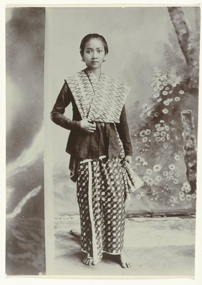 Studio-Porträt einer jungen javanischen Frau in einem Sarong mit Batikmuster und einem Hemd mit Karomuster von Kassian Cephas