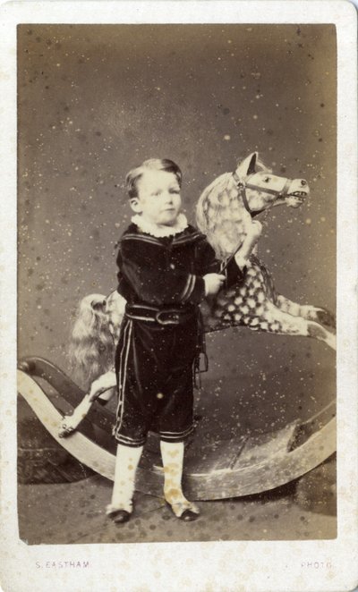 Junger Junge neben einem Schaukelpferd von Silas Eastham
