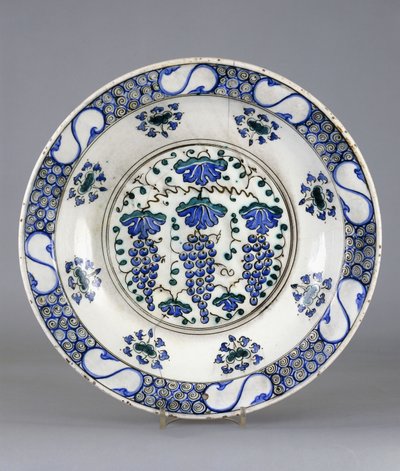 Ein Iznik-Keramikteller, mit einem zentralen Rundel, das drei Traubenbündel und Weinblätter darstellt, ca. 1570 von Turkish School