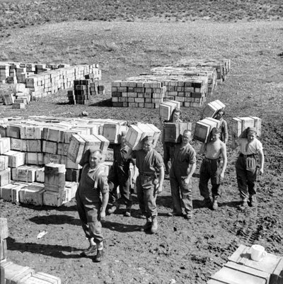 Ein Verpflegungslager und Männer, die mehr Vorräte dorthin tragen, März 1943 von Unbekannt