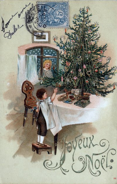 Weihnachtsgrußkarte: Ein Kind vor einem Weihnachtsbaum posiert auf einem Tisch, beobachtet von einem Engel im Fenster - Postkarte von 1905. von Unbekannt
