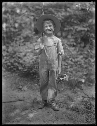William Gray Hassler mit Strohhut und Latzhose, trägt Angelrute und Korb im Wald, 20. August 1911 von William Davis Hassler