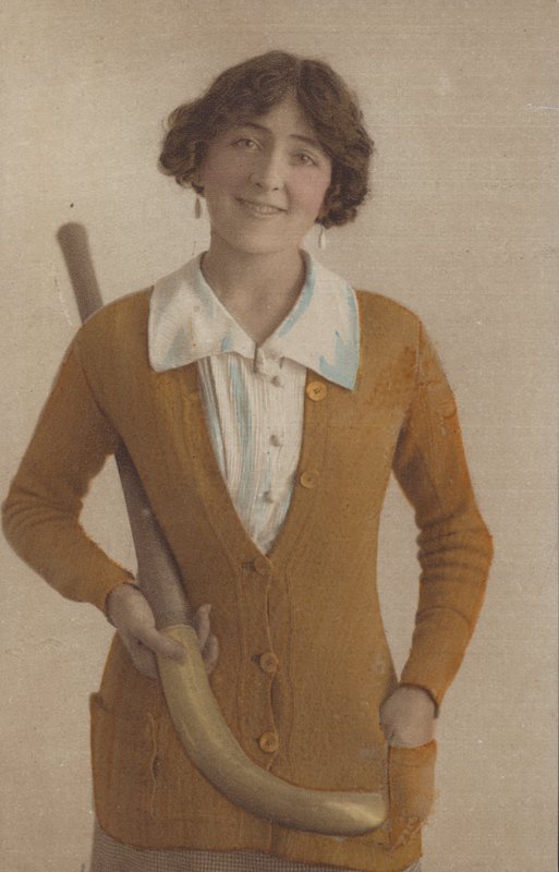 Hübsches Mädchen, im gestrickten Pullover, mit Perlenohrringen, hält einen Hockeyschläger (Foto) von English Photographer