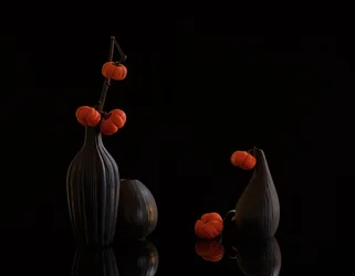 Orangefarbene Kürbisse, dunkle Vasen