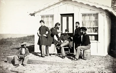 Fünf Soldaten des Bürgerkriegs auf einer Veranda, afroamerikanischer Junge in ihrer Nähe, 1861-65