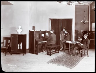 Vier Männer, einer spielt ein H. Bruman Co. Klavier, 1907