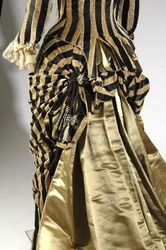 Abendkleid, ca. 1884 (schräge Rückansicht des Bustledetails). Seidensatin und geschnittener Samt, Spitze, Seidenfadenquasten und Fransen. Charles Frederick Worth, Frankreich.