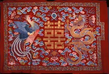Ein chinesischer Wandbehang aus roter Wolle mit einem zentralen Zeichen in Goldfaden, flankiert von einem Phönix und einem Drachen, 19. Jahrhundert
