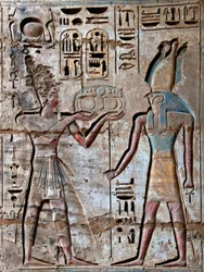 Ägyptische Antike: erster Hof, Detail von bemalten Reliefs, die den Pharao zeigen, der Opfergaben an die Gottheit Horus bringt. Totentempel von Ramses III (1187-1156 v. Chr.). Luxor, Medinet Habu, Ägypten
