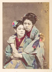 Japanische Frauen in traditioneller Kleidung, Dreiviertelporträt von zwei jungen Frauen, eine sitzt, die andere lehnt sich über ihre Schulter und umarmt sie