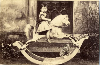 Kleines Mädchen auf einem großen Schaukelpferd im Garten, 1860er Jahre