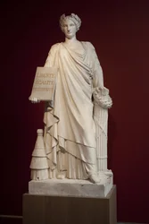 Die Französische Republik. Dargestellt als Frau in antiker Drapierung und mit einer Tafel mit dem Motto „Liberté, Égalité, Fraternité“, der Bienenstock zu ihren Füßen symbolisiert Fruchtbarkeit und Ordnung, die Axt und der Balken sind Machtinsignien, diese