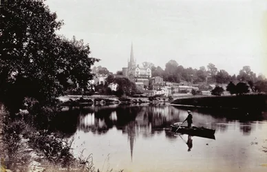 Die Stadt Ross-On-Wye, vom Ufer des Flusses aus gesehen. Im Vordergrund steht ein Mann auf einem Ruderboot