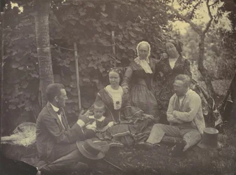 [Drei Frauen, zwei Männer und ein Kind bei einem Picknick]