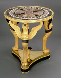 Empire-Gueridon, bestehend aus einer runden Marmortischplatte mit einem zentralen Rosettenmuster, gestützt auf den Flügeln von drei Sphinx-Monopodien, auf einem dreieckigen Ormolu-Sockel, ca. 1800