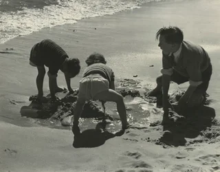 Drei Kinder spielen mit Sand am Strand