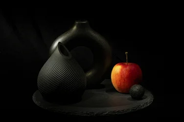 Schwarze Vasen, roter Apfel