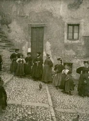 Frauen und Kinder in traditioneller Kleidung auf Stufen, die zu einem Haus führen, Abruzzen, Italien