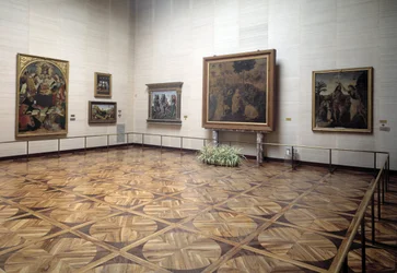 Saal des Museums mit der Darstellung der Anbetung der Könige von Vinci, der Taufe Christi von Verrocchio und Vinci, der Heiligen Dreifaltigkeit mit der Jungfrau und den Heiligen von Signorelli