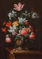Tulpen und andere Blumen in einer bemalten barocken Steingutvase auf einem Holzvorsprung