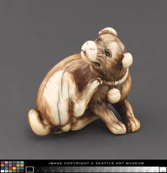 Netsuke modelliert als Hund, der sich am Hals kratzt