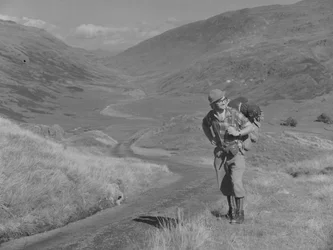 Ein Mann geht mit einem Rucksack auf dem Rücken in einer offenen Tal-Landschaft