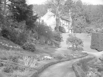 Ein helles Gebäude umgeben von gestalteten Gärten