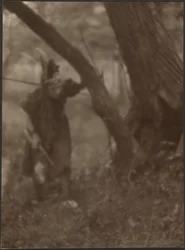 Frau mit Kopfschmuck hinter Baum