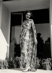Model trägt ein langes Kleid mit Blumenmuster, kreiert von der Couture-Haus "Graldi". Der Artikel wird durch einen Mantel aus demselben Stoff ergänzt.