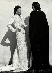 Zwei Modelle präsentieren Kreationen des italienischen Modehauses "Dragoni". Ein Modell trägt ein Outfit aus gemustertem Material, bestehend aus einer Jacke und einem langen Rock mit Schleppe. Das andere Modell, von hinten gesehen, trägt einen langen Samtu