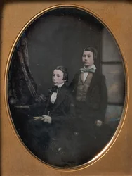 Zwei junge Männer mit Fliegen, einer sitzt und hält ein Buch, einer steht, 1850er Jahre