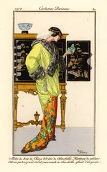 Frau im Seidenkleid mit Chinchillabesatz, zitronengrüner Samtumhang mit Chinchillakragen und -manschetten, hält einen Jade-Buddha. Chinesischer Schrank im Hintergrund.