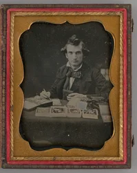 Unbetiteltes Porträt eines sitzenden Mannes, der ein Daguerreotyp und einen Pinsel hält, 1865