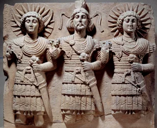 Palmyrenische Trias: Baalshamin, Herr des Himmels, zwischen dem Mondgott und dem Sonnengott. Kalksteinflachrelief aus dem 1. Jahrhundert. Aus Palmyra, Syrien. Maße: 0,6 x 0,72 m. Paris, Musée du Louvre