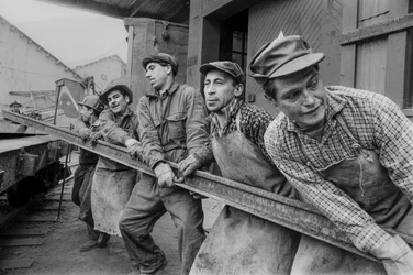 Bergarbeiter ziehen zusammen, um eine schwere Stahlschiene in der El Teniente-Kupfermine zu bewegen...