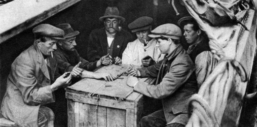 Ein Schiffer und seine Kameraden spielen Domino im Laderaum eines Kanalbootes, 1926-1927
