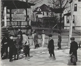 Eine Gruppe von Jungen in Wintermänteln steht auf einer unbekannten Straße entweder vor oder nach einem Schultag.