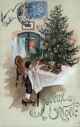 Weihnachtsgrußkarte: Ein Kind vor einem Weihnachtsbaum posiert auf einem Tisch, beobachtet von einem Engel im Fenster - Postkarte von 1905.